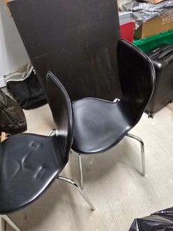 Two black faux leather and stainless steel chairs.