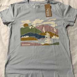 NWT Eddie Bauer Graphic T-Shirt Colorful Mountain Layers Scene Birds Clouds Sun Women’s Small  Features a soft light blue background with a colorful m