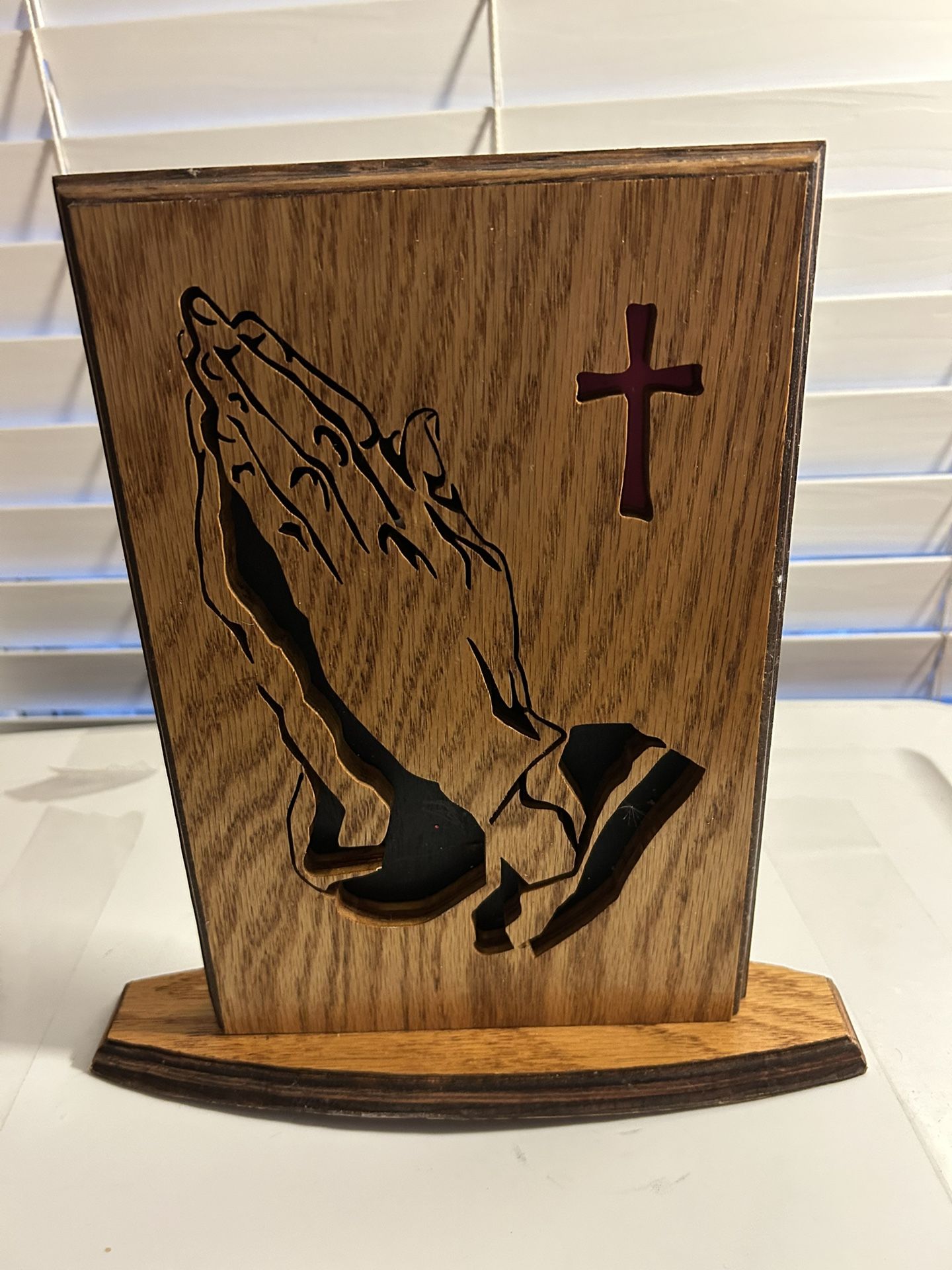 Wooden religious accent piece featuring a cutout design of praying hands and a cross