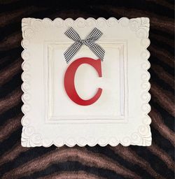 Monogram plaque with red capital letter "C” accented with a gingham fabric  black-and-white checkered bow