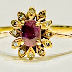 Beautiful Ruby center stone with diamonds set in a flower design set in 14k yellow gold size 7