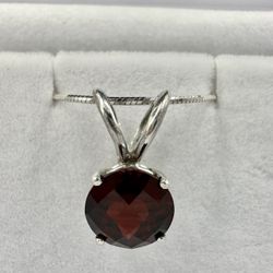 round 7mm garnet set in a sterling silver pendant with a sterling silver snake chain
