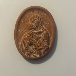 This is a terracotta Orthodox icon of the Virgin Mary and Child. It depicts the Madonna and Child in a style common in Christian art