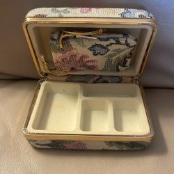 The item shown is a Mundi jewel case, specifically a vintage, hard-shell travel jewelry box with a floral tapestry or fabric cover.