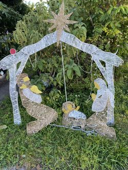 outdoor Christmas Nativity scene featuring the Holy Family under a lighted arch with a star on top