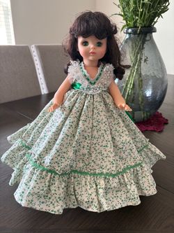 Vintage Madame Alexander doll: dark brown hair, wearing a green floral dress.
