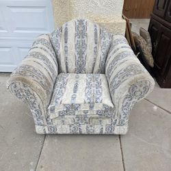This is a floral and striped upholstered lounge chair. 
