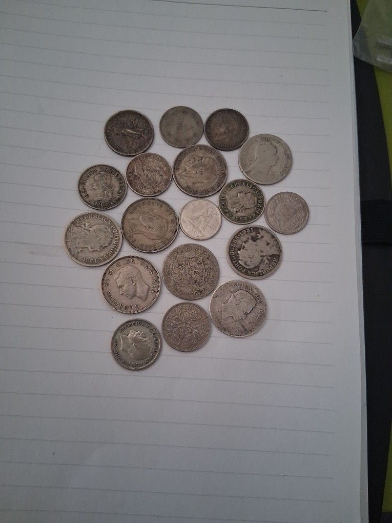 collection of vintage, circulated world coins, which likely include a mix of foreign silver and base metal coins.