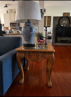 Beautiful pair of ornate end tables featuring detailed carved scrollwork, elegant curved legs, decorative feet, rich wood grain tops, and inset glass