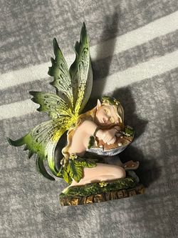 Green fairy sleeping on mushroom statue