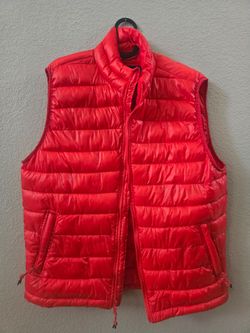 Lightweight quilted puffer vest in vibrant red. Insulated design for warmth without bulk. Zipper front and hand pockets for secure storage. Stand coll