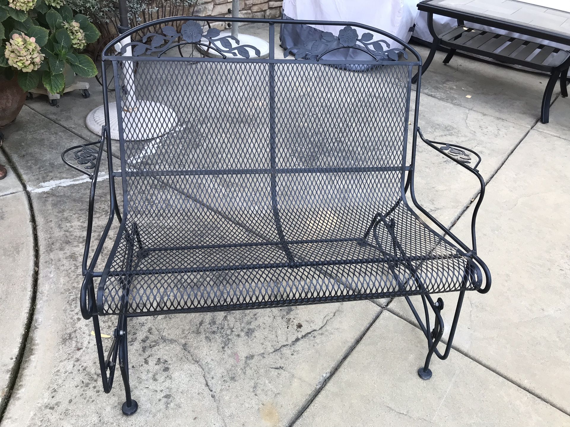 A beautiful wrought iron garden glider bench 