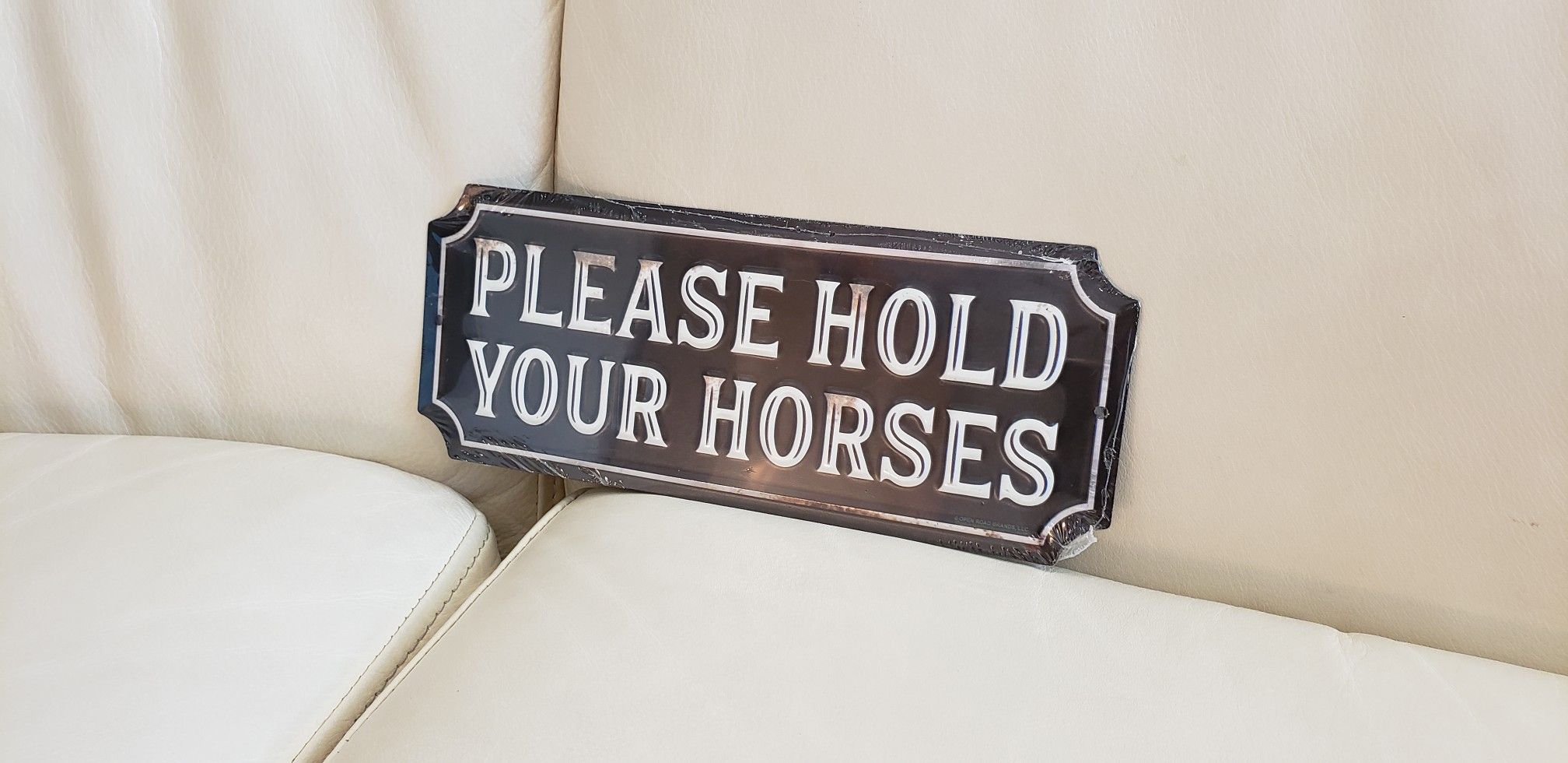 Please hold your horses embossed metal equestrian funny horse riding rodeo barn stall farm backyard decoration. Brown & white measures 10" x 4"
