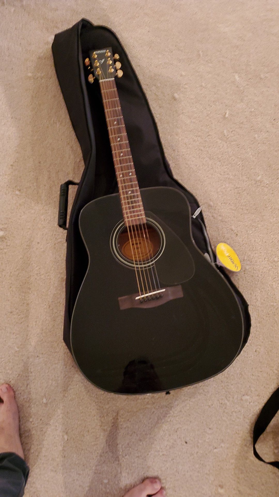 Black Yamaha guitar with case and a capo