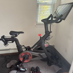 Peleton Bike, Two Pairs Of Shoes, and pair of 3 pound Weights and Peleton Mat
