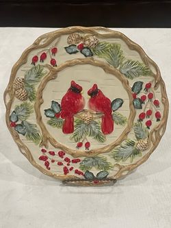 Decorative ceramic holiday plate featuring sculpted red cardinals and pine branches. 10”