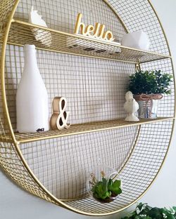 Gold Metal Round Wall shelf 25” features a gold-finished wire mesh design with two interior shelves