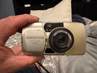 Vintage Olympus Stylus Zoom 105 is a champagne gold 35mm point-and-shoot film camera. It has an Olympus 38-105mm zoom lens and built-in flash. This co