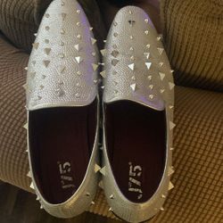 This is a pair of silver spiked loafers. 