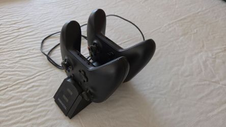 two black Xbox wireless controllers docked with dual-chargin