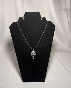 silver-colored metal pendant necklace and matching stud earrings