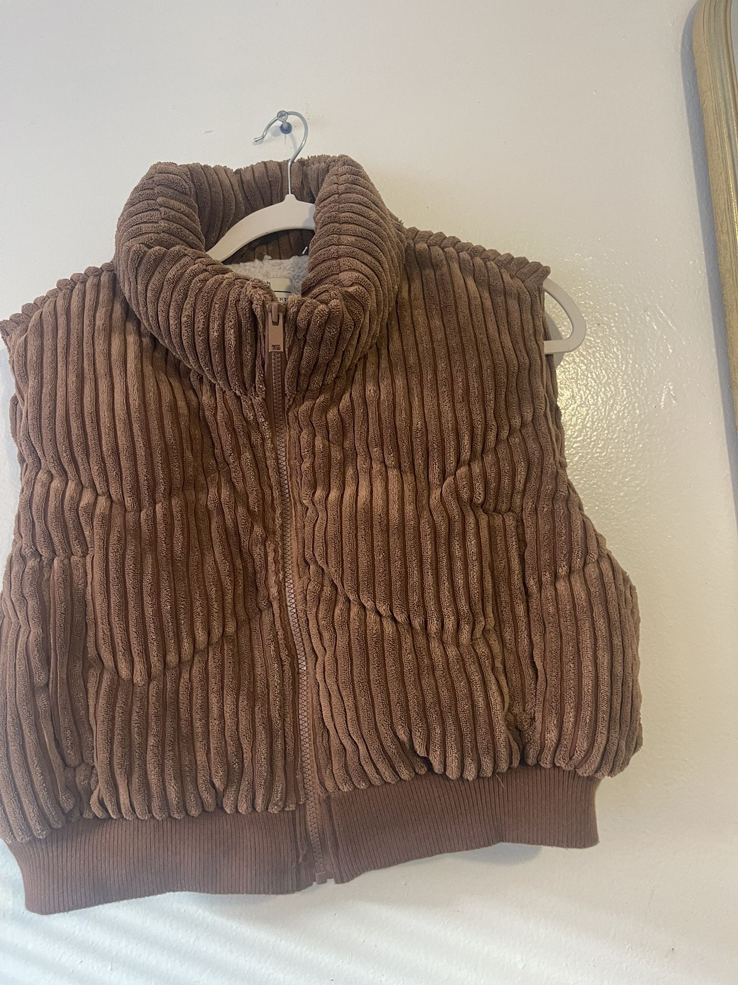 This is a Miss Posh brown corduroy puffer vest with a sherpa lining. 