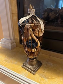 decorative bronze-toned metal wire urn or pedestal basket filled with dried potpourri and natural botanicals.