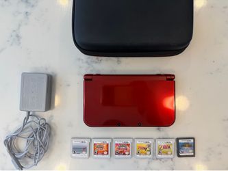 Nintendo 3DS XL with games, charger, and case