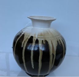 A large vintage/art-pottery ceramic vase with a black, cream/tan drip glaze