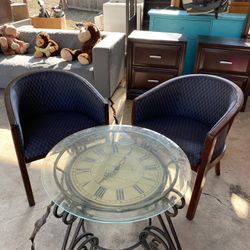 Round glass side table with a wrought iron base and a clock design.