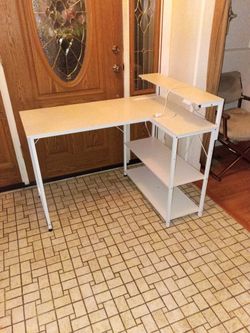White L shaped desk with power cord and plug in strip