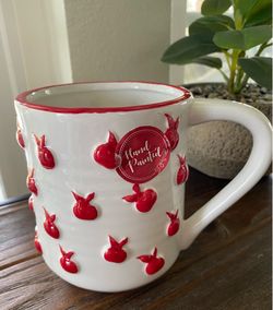 This Sheffield Home ceramic mug features a white base with raised red apple designs and a "Hand Painted"
