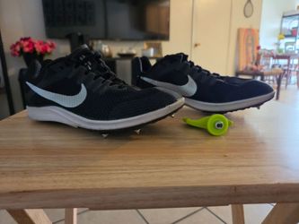 black and metallic silver Nike Zoom Rival Distance Track & Field Spikes featuring a mesh upper, white Swoosh, and a spiked sole.