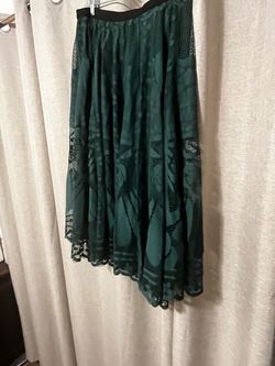 Elegant dark green midi skirt with a floral lace overlay. This piece has a black elastic waistband and a full, pleated silhouette. The lace features a