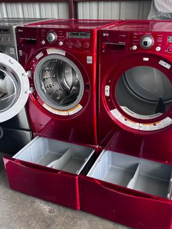 Red front LG washer and  front load LG dryer electric high efficiency with pedestals.