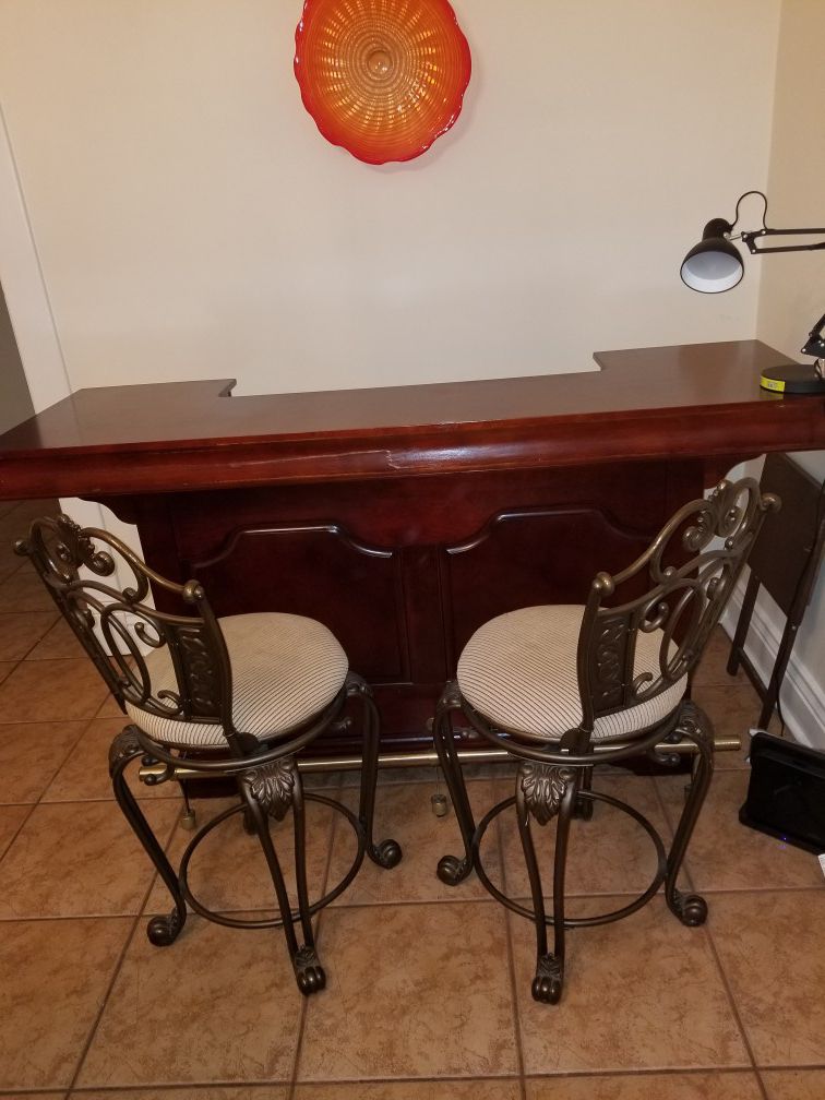 Solid wood wet Bar. Two beautiful matching metal bar stools. Seats fully rotate.