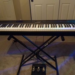 Black keyboard with weighted keys a foot pedal and stand and different functions and headphones