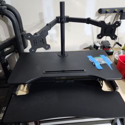 Black dual monitor stand with adjustable arms and desk riser.  With 2 monitors.