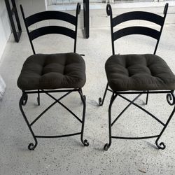 2 Beautiful wrought iron chairs featuring scrollwork legs and plush tufted cushions.