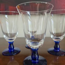 Set of four hand-blown clear glass goblets with cobalt blue stems and feet.