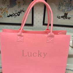 Bubble gum Pink felt tote  lucky written across front  2 handles  Measures 15.5”