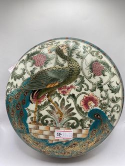a vintage round porcelain trinket or powder box featuring a hand-painted peacock