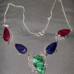 Handmade statement necklace featuring large teardrop stones in green, deep blue, and raspberry red tones set in silver metal. 