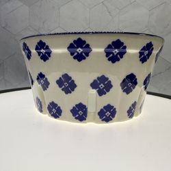 This is an American Atelier ceramic berry basket with a blue stamp design. It’s is a round, white ceramic container with a blue rim and blue floral pa