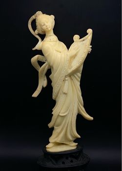 A vintage cream-colored celluloid or plastic Asian harp-playing figurine