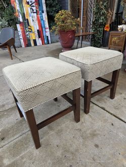 a pair of upholstered stools with dark wood legs.