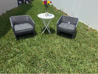 Two outdoor chairs with cushions and table