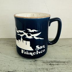 Vintage stoneware souvenir San Francisco mug.  Navy blue. Seagulls and Golden Gate Bridge. Marked SNCO. Holds 10 oz. 3 3/4” tall.  Speckled inside. 
