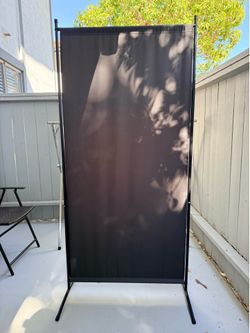 Versatile single-panel privacy screen has a black fabric panel and a matching black metal frame.