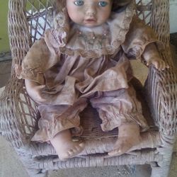 Porcelain Doll On Wicker Chair 